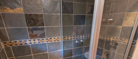 A bathroom with a glass-enclosed shower, a sink, and a toilet.