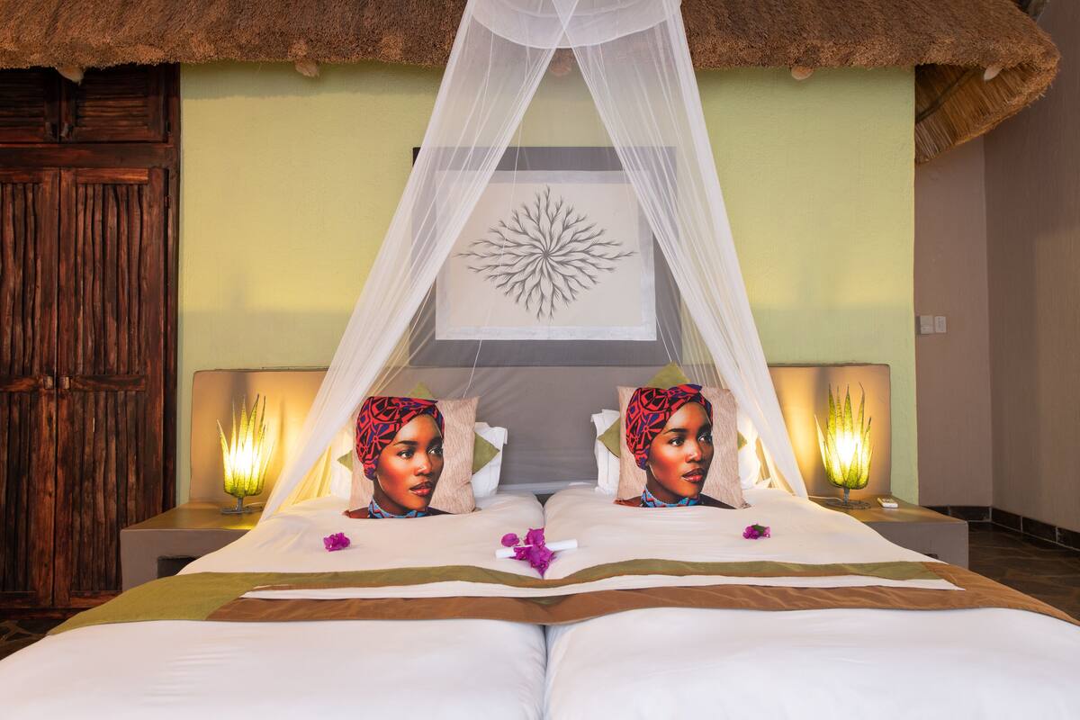 A bed with a canopy, two bedside lamps, and a decorative wall piece.
