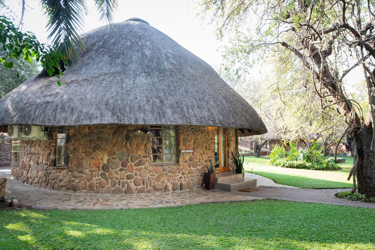 A stone building with a thatched roof labeled "Cul House," surrounded by a well-maintained lawn and trees.