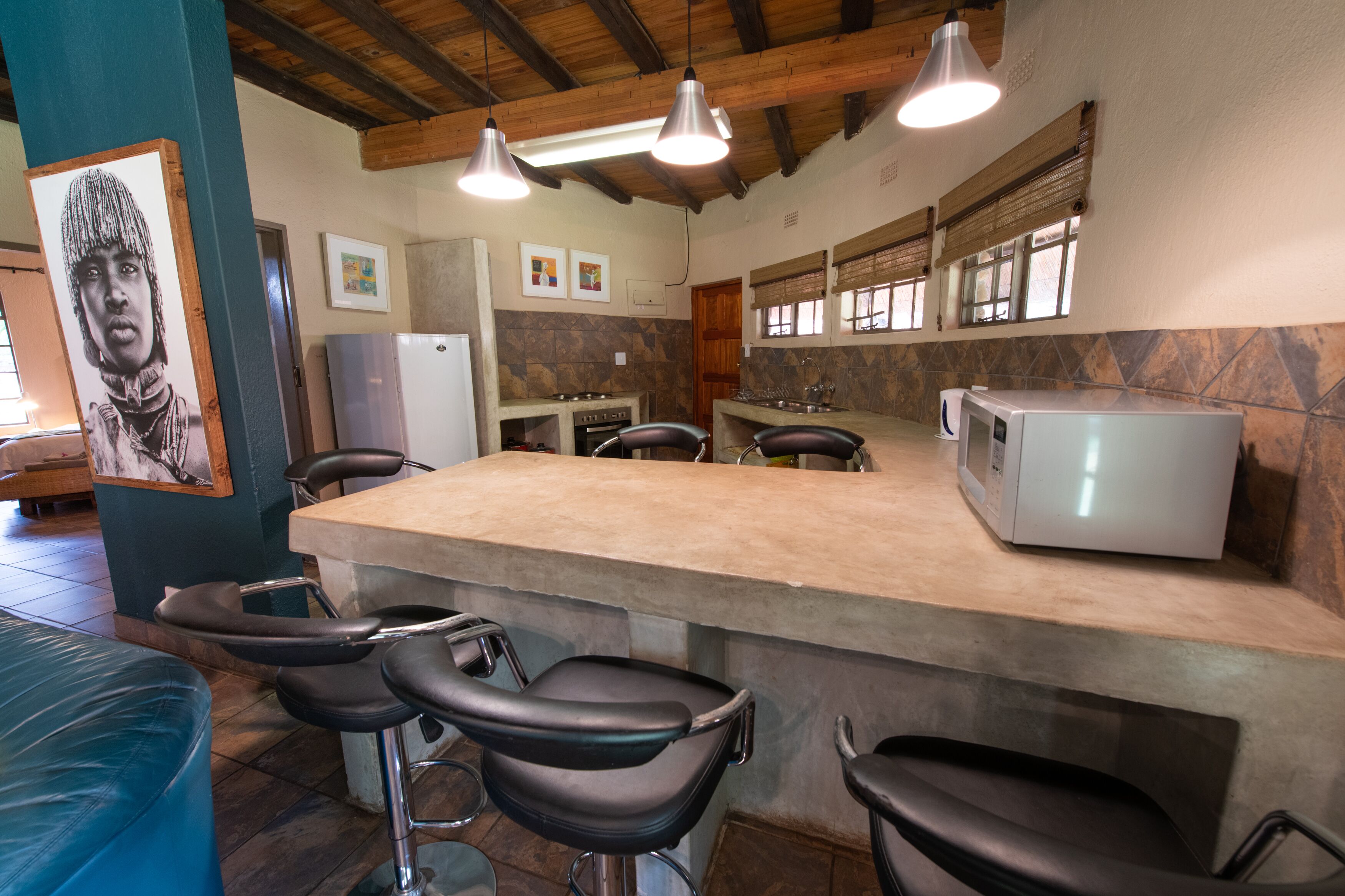 Una cocina con barra, que presenta un salpicadero de piedra, vigas de madera en el techo y electrodomésticos modernos.