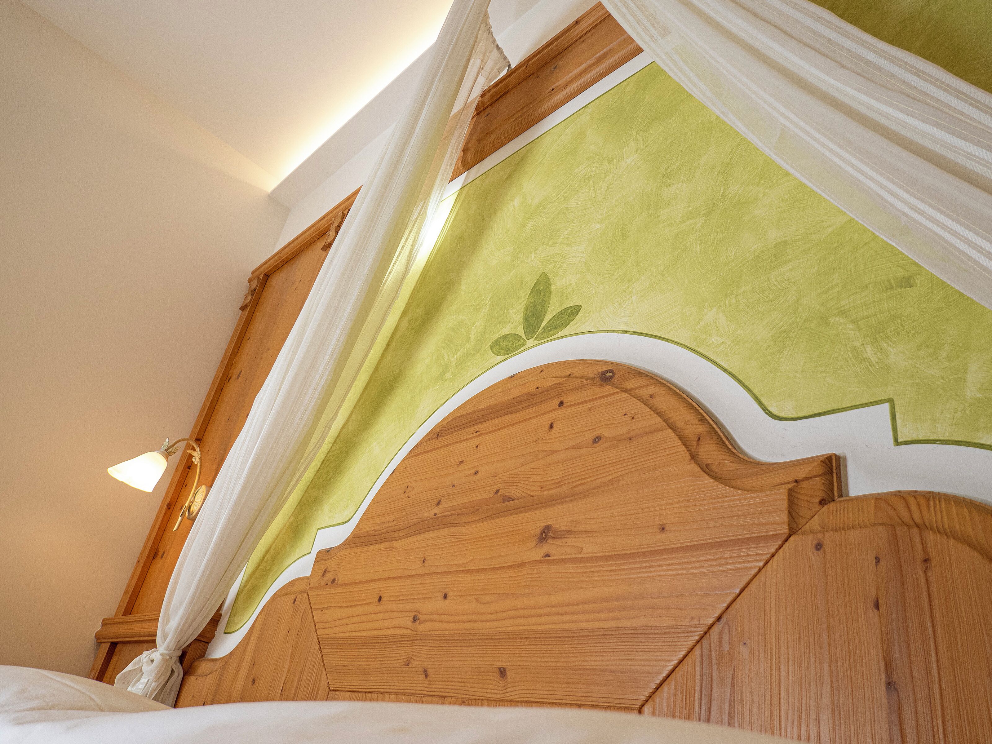 A wooden headboard with a green fabric canopy.