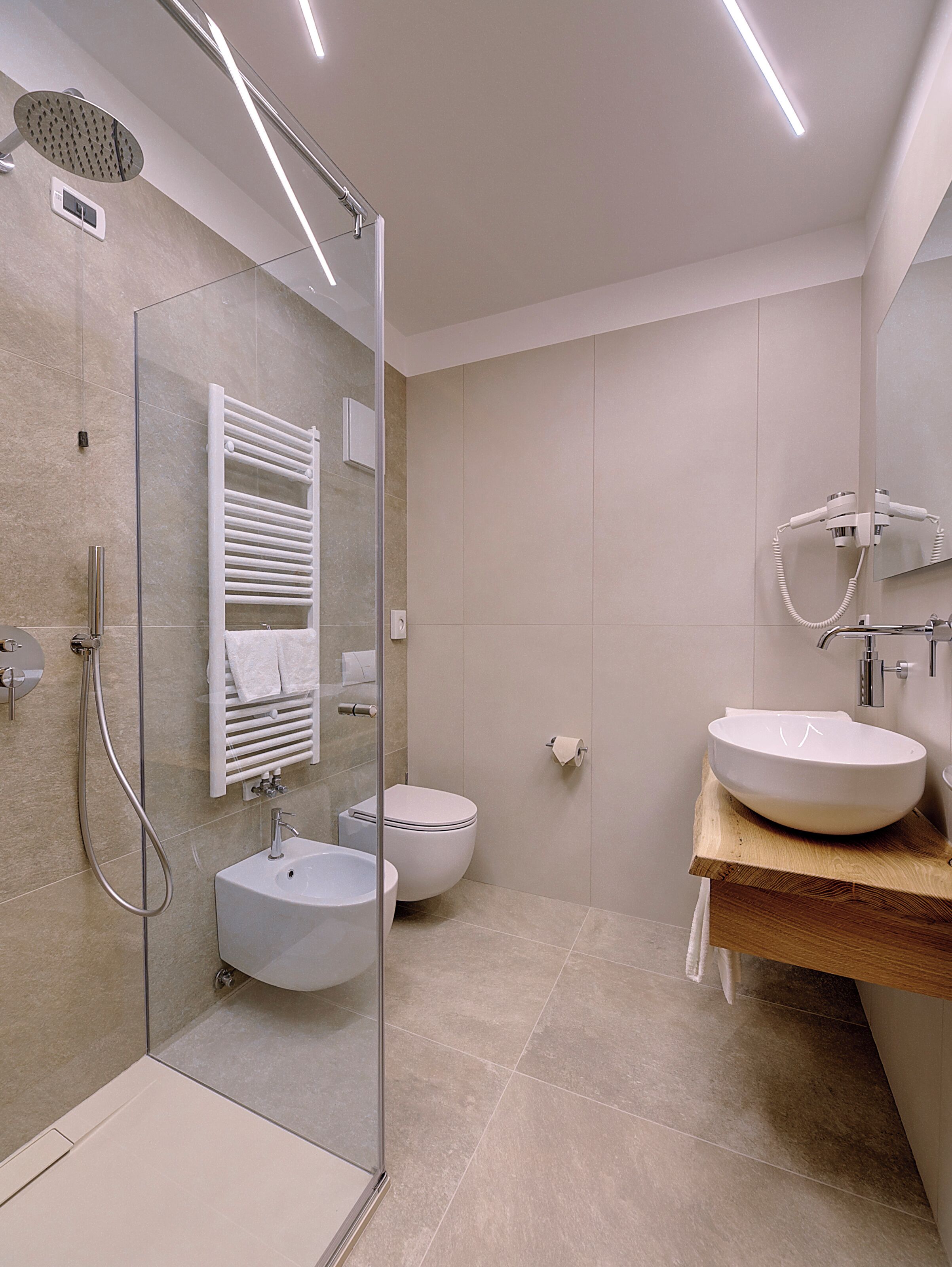 Un baño moderno con cabina de ducha de vidrio, un lavamanos blanco y un inodoro.