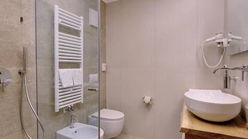 A modern bathroom with a glass shower enclosure, a white sink, and a toilet.