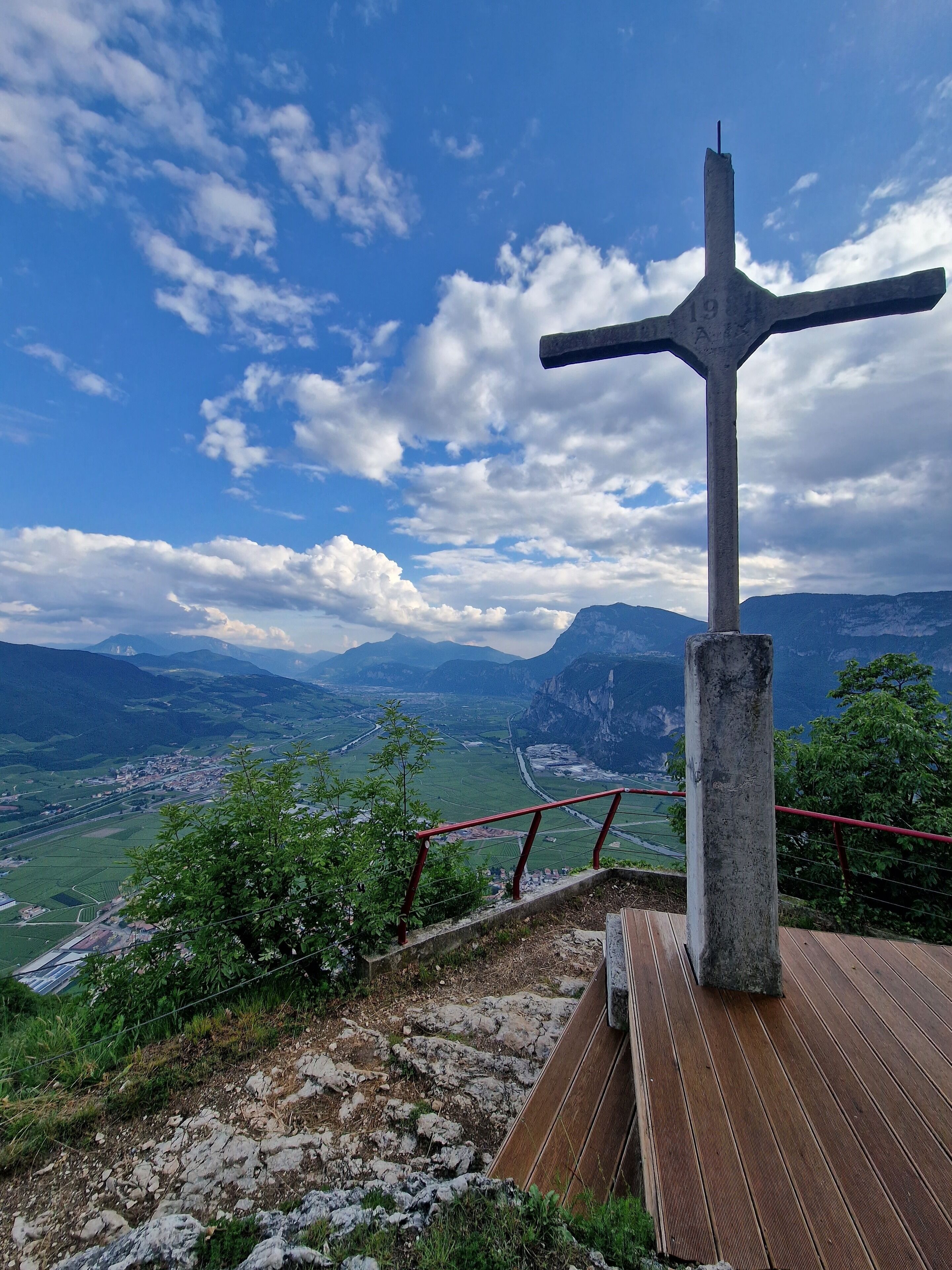 Un monument en forme de croix, placé sur une plateforme en bois, d’où l’on peut admirer une vallée et des montagnes.