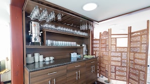A kitchen with a coffee machine, glassware, and a wooden cabinet. - Hotel Fontibon (Bogotá)