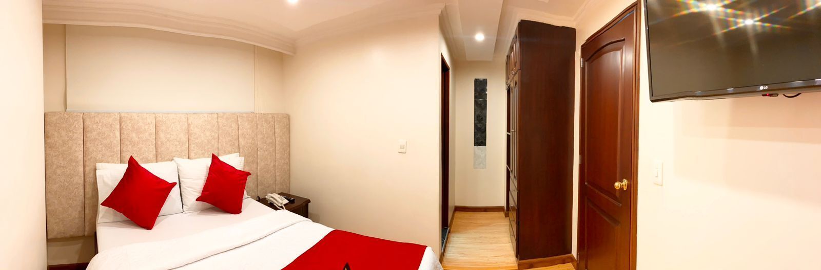 A hotel room with a bed, a bedside table, a TV, and a wardrobe.