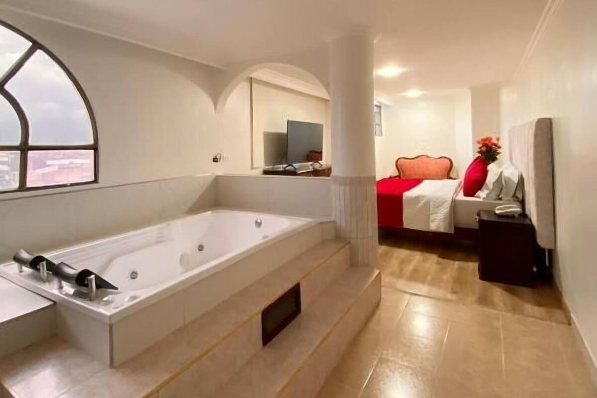 Een moderne badkamer met een ruime badkuip, een wastafel met spiegel en een raam.