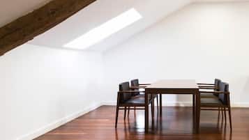 Ein Essbereich mit Holztisch und -stühlen, weißen Wänden und einer geneigten Decke mit freiliegenden Balken.