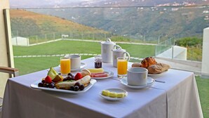 Una mesa de desayuno con diversos alimentos y vistas a un paisaje montañoso.