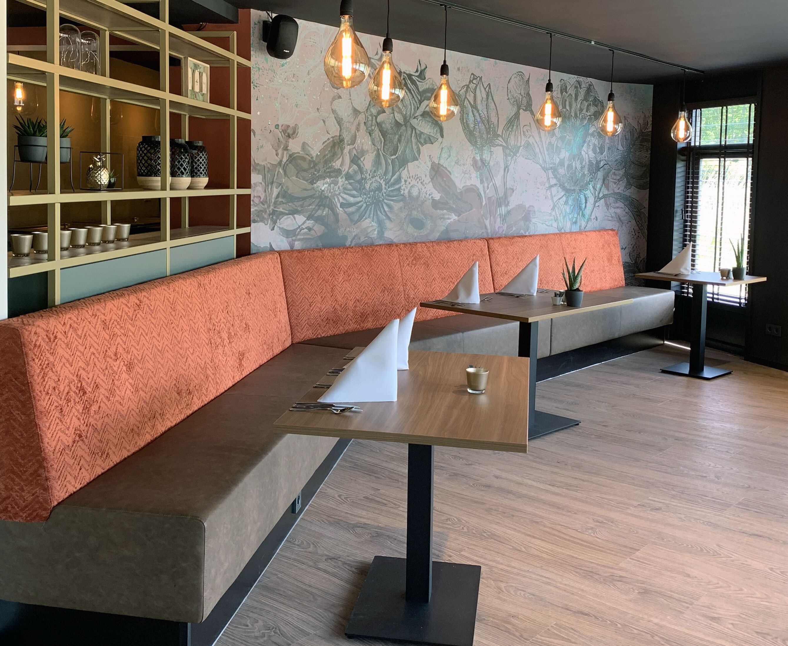 Un interior moderno con un sofá naranja de diseño chevron, una mesa de madera y una pared con un mural floral.