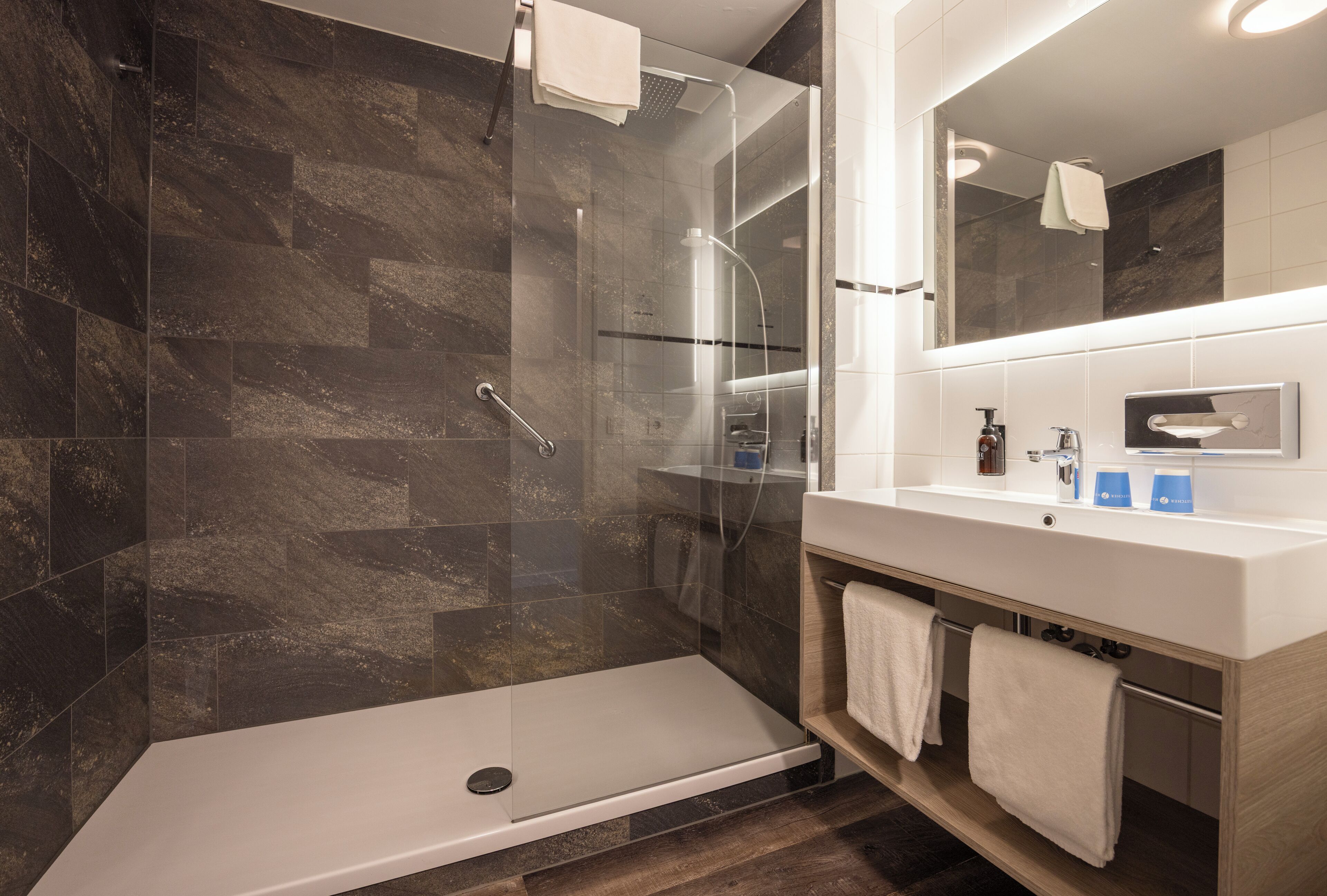 Une salle de bain moderne avec une douche à parois de verre, un meuble-lavabo avec un miroir et un évier.