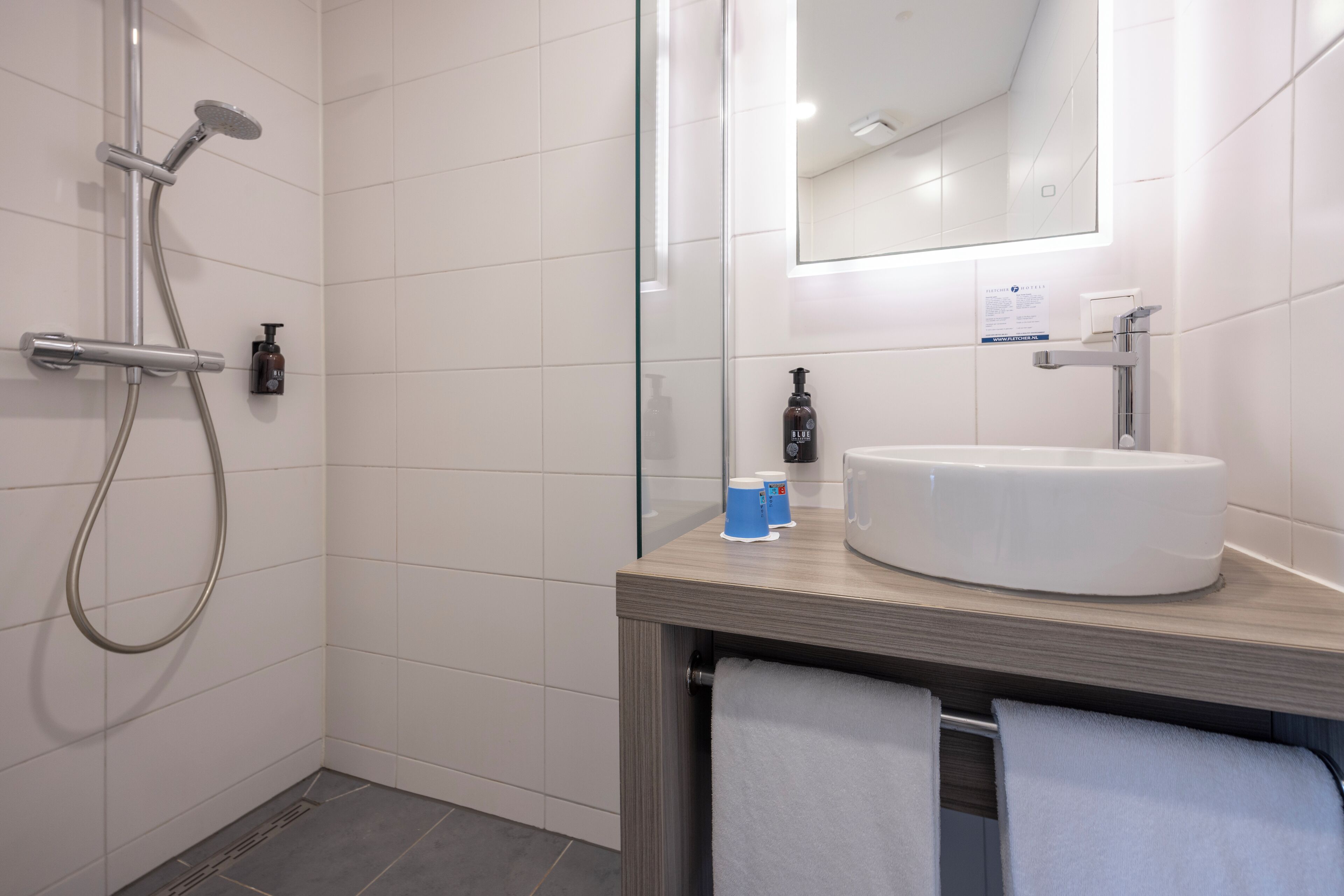 A modern bathroom with a shower, a sink, and a mirror.
