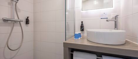 A modern bathroom with a shower, a sink, and a mirror.