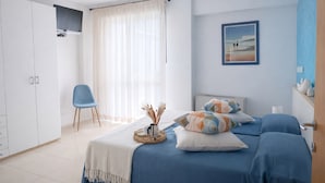 A bedroom with a bed, a wardrobe, a chair, and a painting on the wall. - Residence I Delfini (Cupra Marittima)