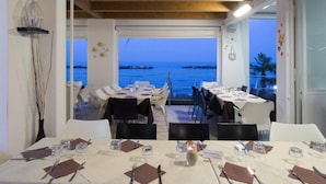 A dining area with tables set for a meal, overlooking a body of water. - Residence I Delfini (Cupra Marittima)