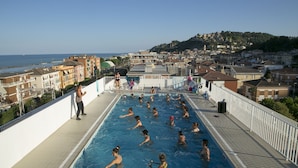 A swimming pool with people in it, overlooking a town and the sea. - Residence I Delfini (Cupra Marittima)