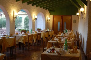 Un restaurante con mesas preparadas para comer, con una decoración rústica que incluye arcos e iluminación en las paredes.