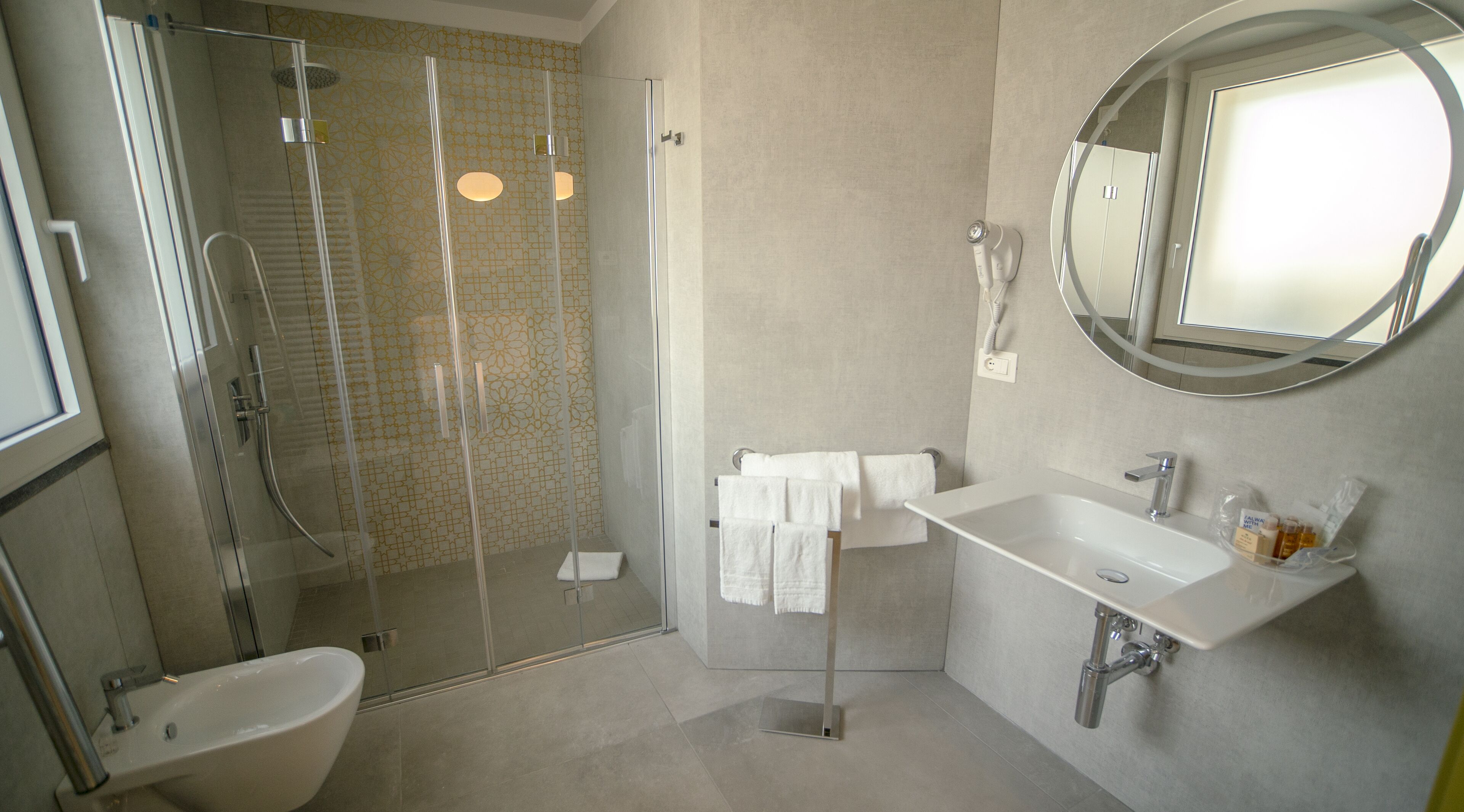A modern bathroom with a glass-enclosed shower, a white sink, and a large mirror.