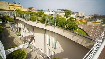 A multi-level residential building with balconies, railings, and greenery.