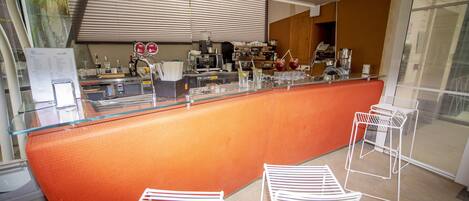 A modern bar area with a curved orange counter, white metal chairs, and a variety of bar equipment.