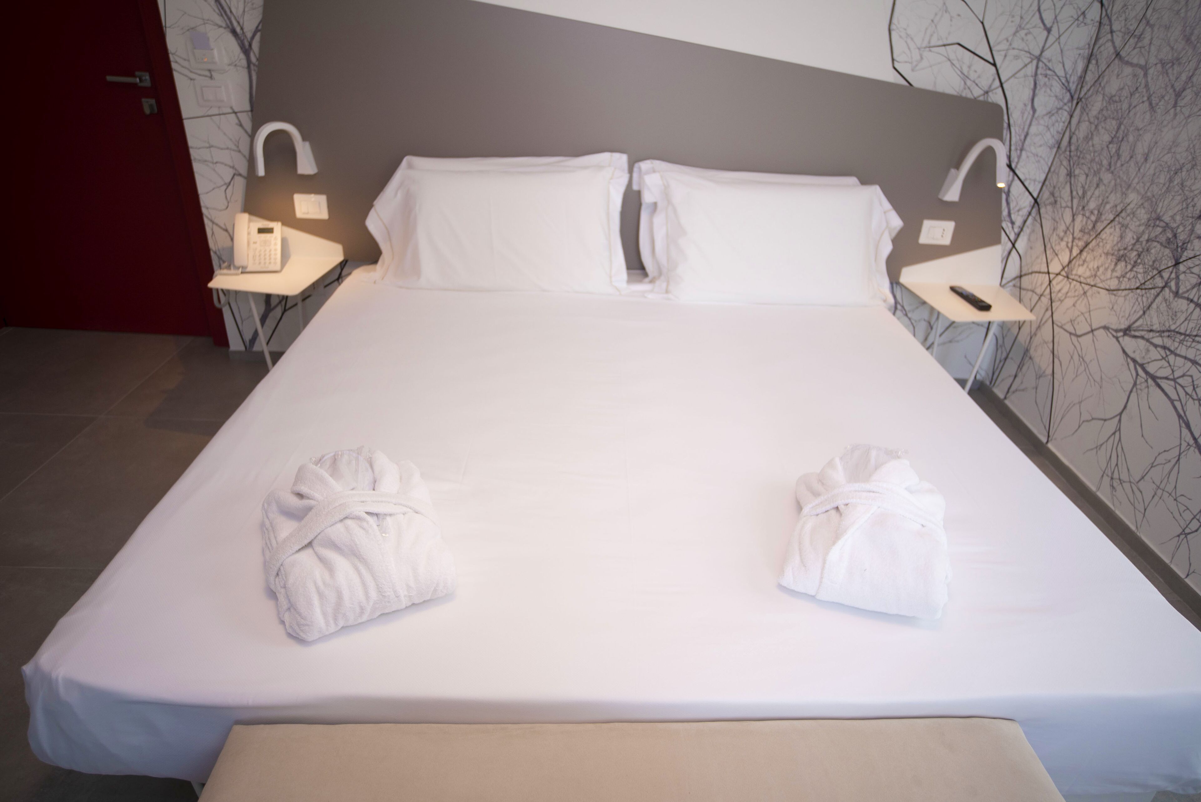 Una cama bien hecha con sábanas blancas y dos toallas dobladas al pie.