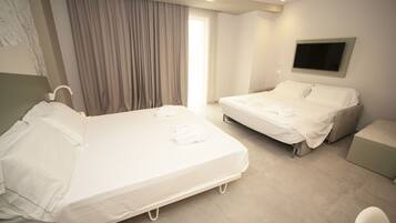 A hotel room with two beds, a TV mounted on the wall, and a window with curtains.