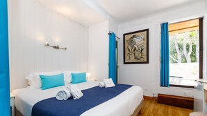Ein Hotelzimmer mit einem großen Bett, einem Gemälde an der Wand und einem Fenster mit Vorhängen.