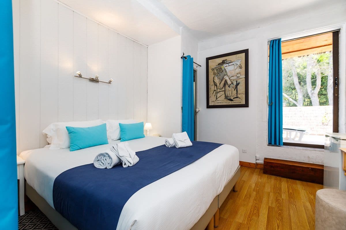 Een hotelkamer met een groot bed, een schilderij aan de muur en een raam met gordijnen.