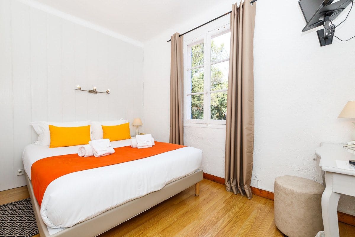 Een hotelkamer met een bed, een bureau en een raam met gordijnen.