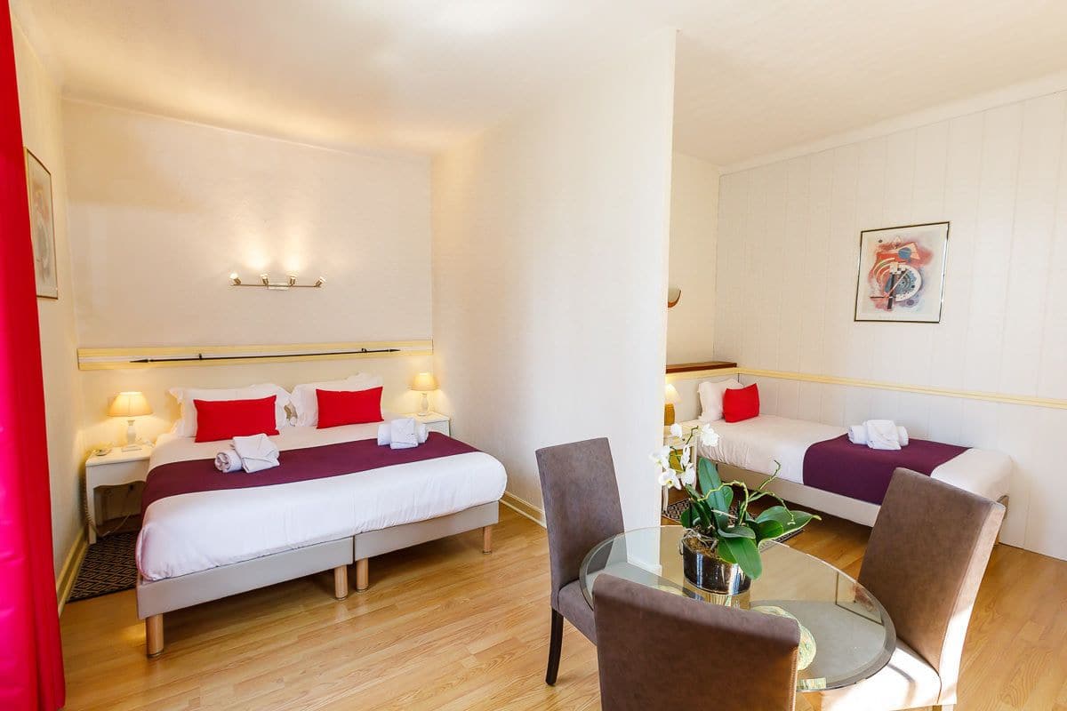 Een hotelkamer met twee bedden, een glazen tafel en een stoel.