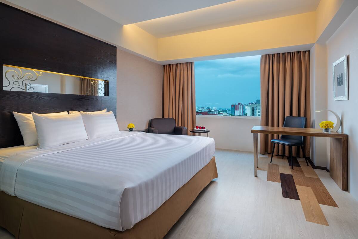 Habitación de hotel moderna con una cama grande, un escritorio y vistas a la ciudad.
