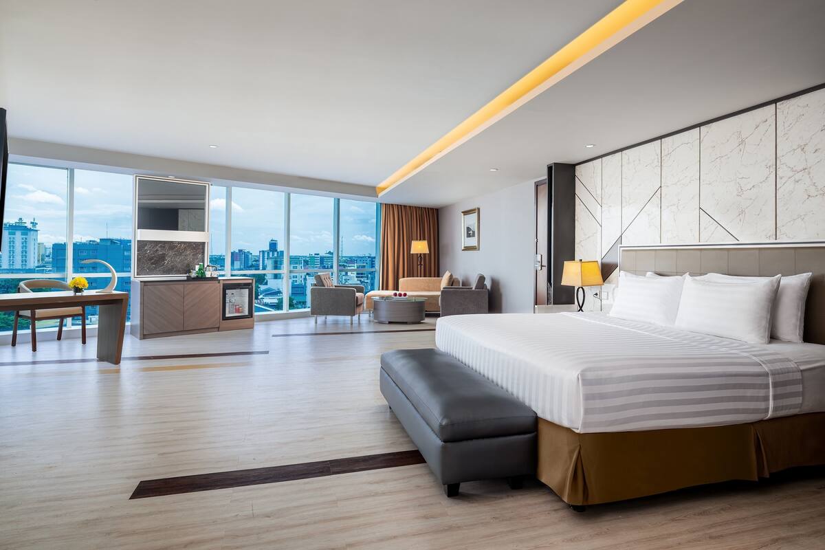 Una habitación de hotel moderna con una cama grande, un escritorio y vistas a la ciudad.