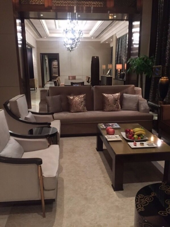 A modern living room with a sofa, armchairs, a coffee table with fruit, and a chandelier. - Tianjin Goldin Metropolitan Polo Club (Tianjin)