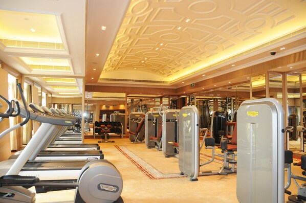 A gym with treadmills, weight machines, and a mirrored wall.