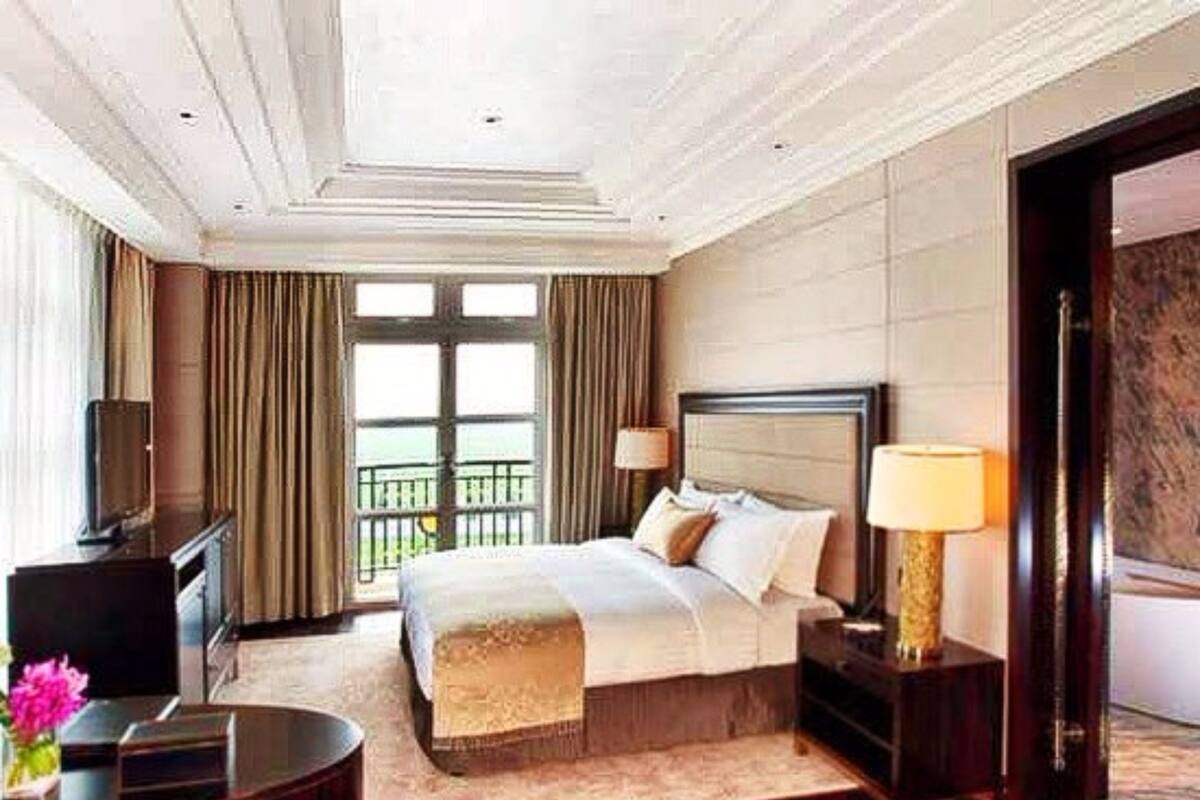 Habitación de hotel con una cama grande, televisión, escritorio y vistas al balcón.