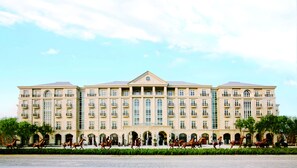 A large, multi-story building with a symmetrical facade, numerous windows, and a central entrance with a triangular pediment.