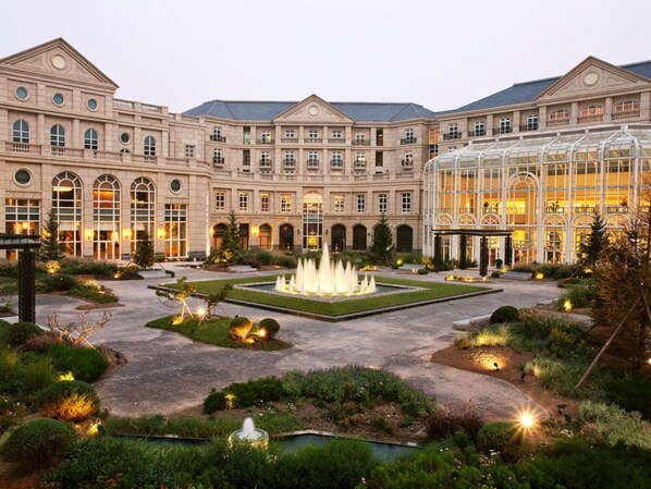A large hotel with a central courtyard, a fountain, and a conservatory.