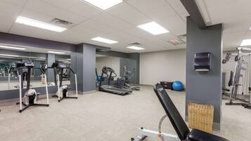 Een sportschool met diverse fitnessapparaten, waaronder loopbanden, elliptische trainers en krachtapparaten.