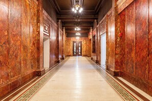 A long, ornate hallway with marble walls and a patterned floor, leading to a set of double doors. - Hotel at the Lafayette Trademark Collection by Wyndham (Buffalo)