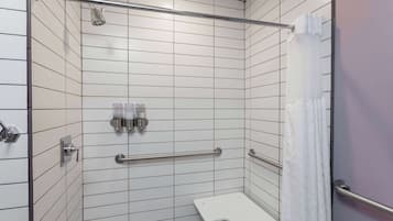 A shower with white tiles, a grab bar, and a showerhead.