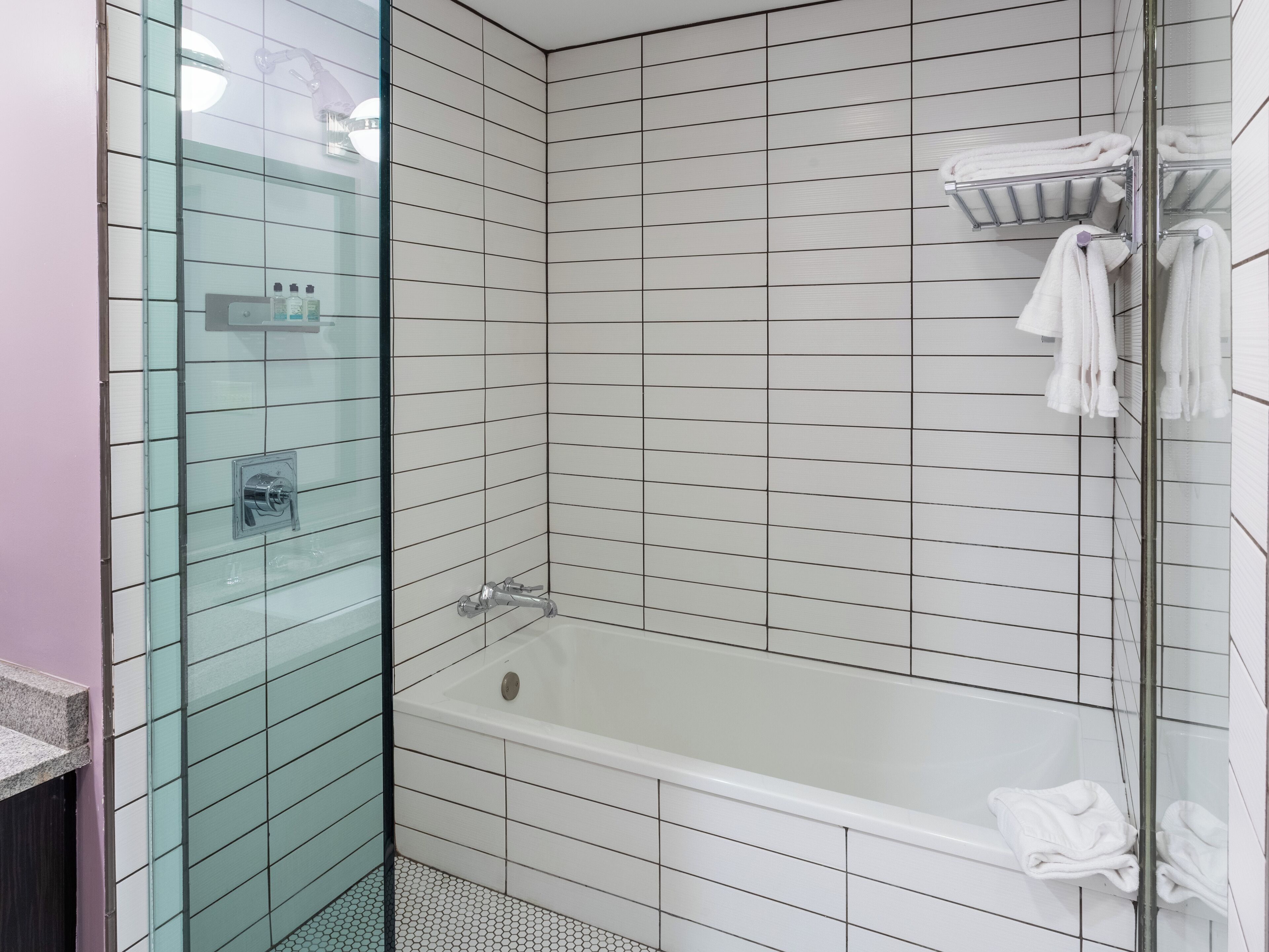 A modern bathroom with a glass-enclosed shower, a white bathtub, and a tiled shower area.