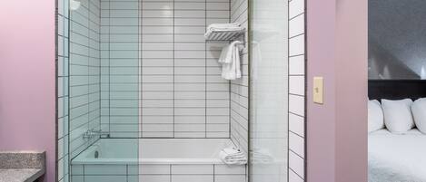 Un baño moderno con cabina de ducha de vidrio, bañera y piso de baldosas.