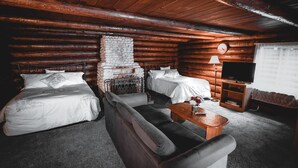 Een blokhutkamer met twee bedden, een bank, een televisie en een open haard.