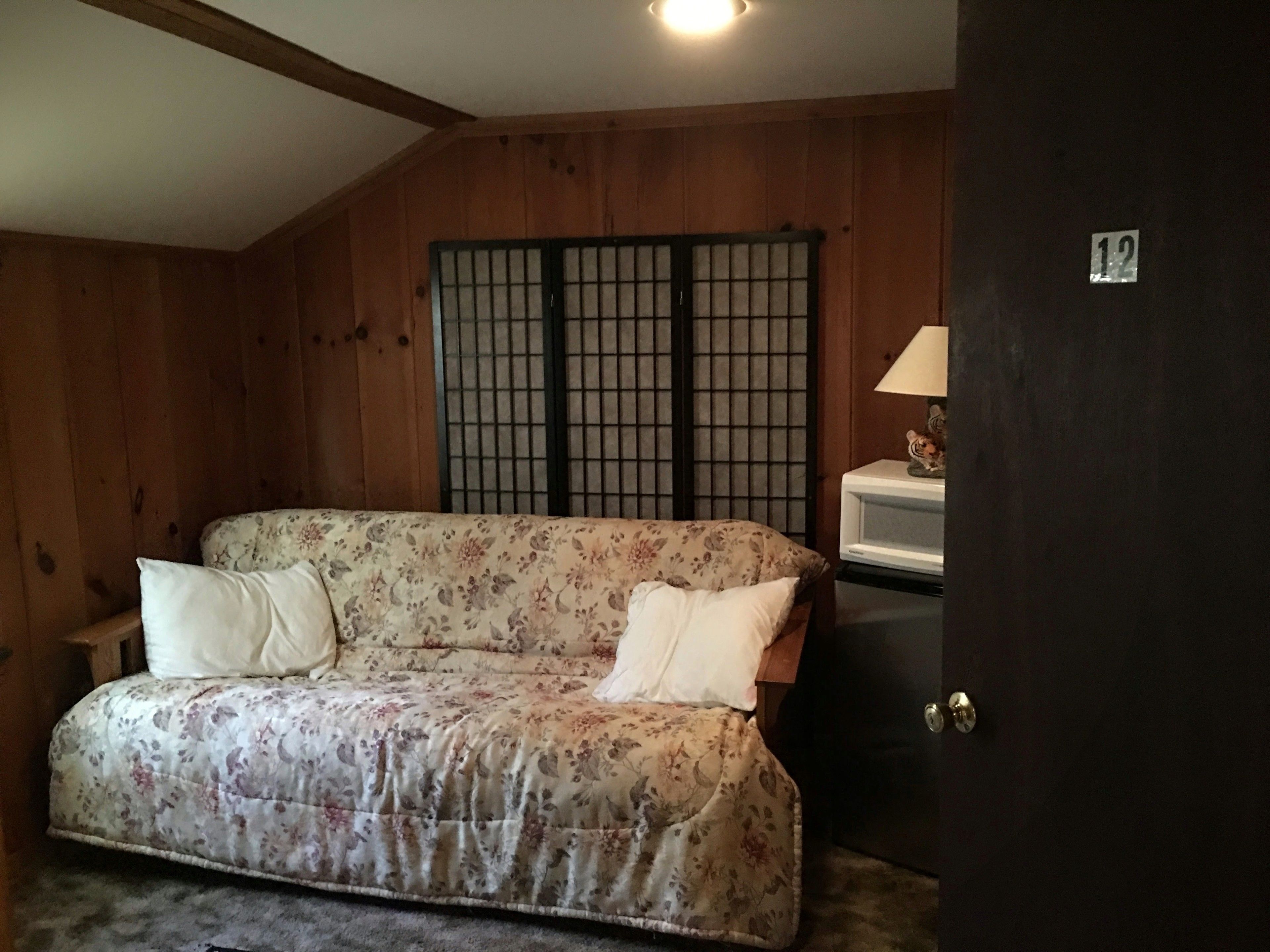 Ein Zimmer mit einem floralen Sofa, einer Holzwand und einer Tür mit einer Nummernaufkleber.