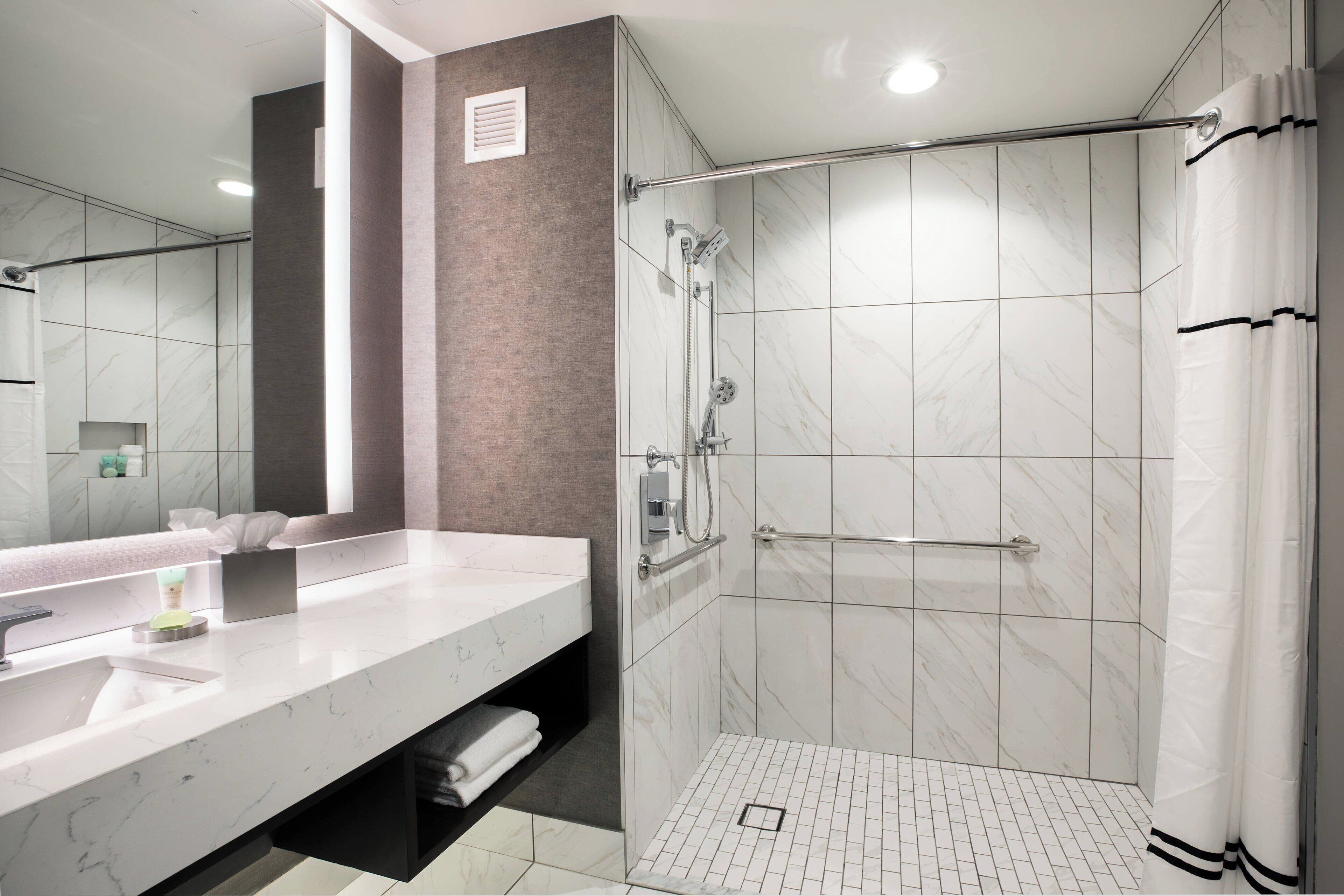 A modern bathroom with a marble vanity, a glass shower enclosure, and a towel rack.