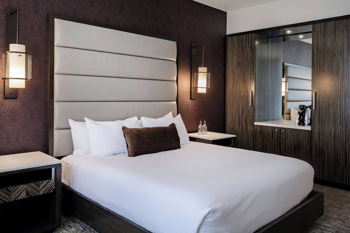 Ein Hotelzimmer mit einem großen Bett, zwei Nachttischen, einem Spiegel und einem Kleiderschrank.