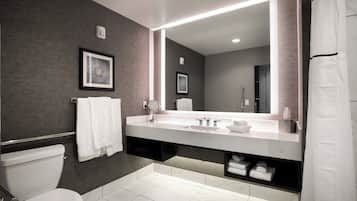 A modern bathroom with a large mirror, white fixtures, and a towel rack.