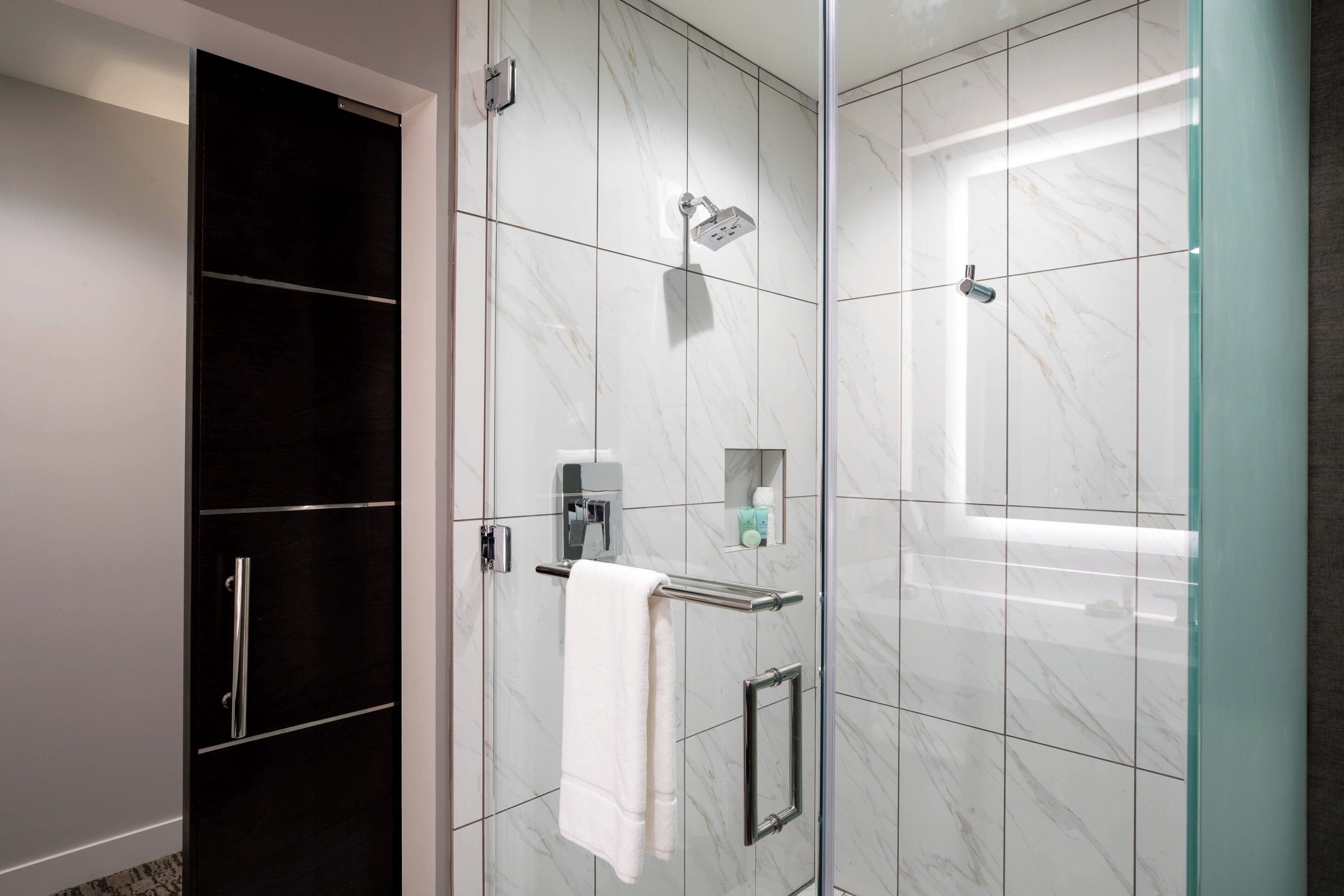 A modern bathroom with a glass shower enclosure, a towel rack, and a built-in cabinet.