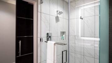 A modern bathroom with a glass shower enclosure, a towel rack, and a built-in cabinet.