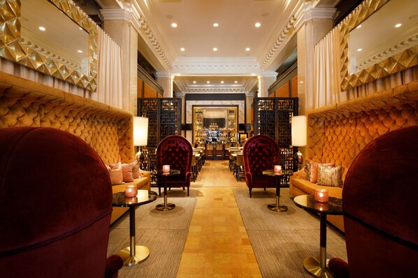 Relax in the elegant lobby, featuring plush seating and a grand mirror.